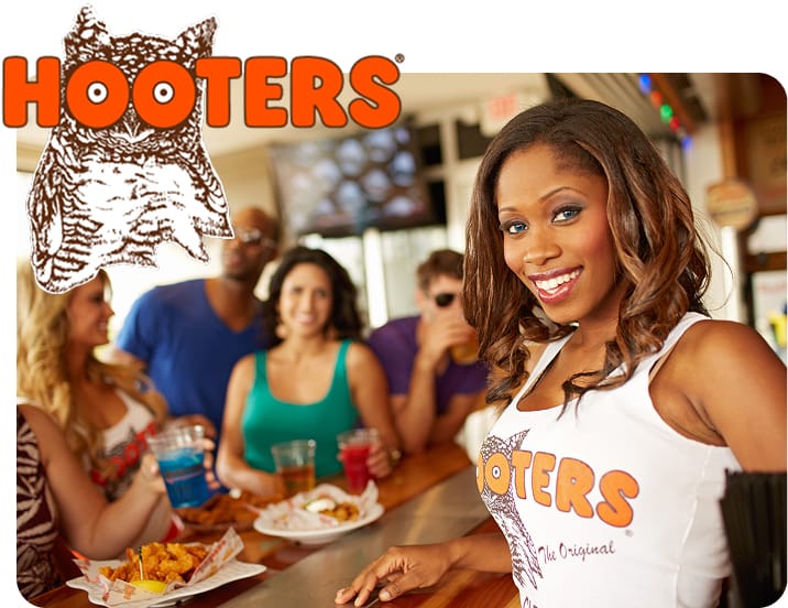 A Hooters waitress carrying a plate of wings